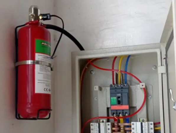 Wall-mounted fire suppression cylinder beside an open electrical panel
