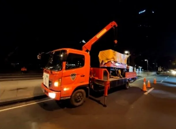 Orange boom truck carrying a load on a road at night