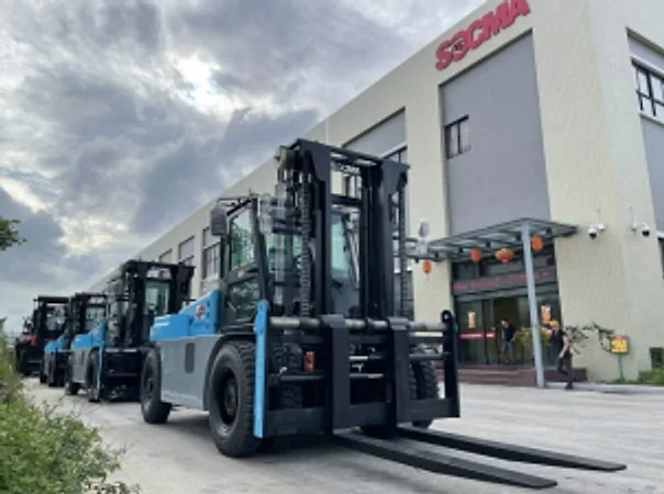 Row of new blue forklifts parked outside a building