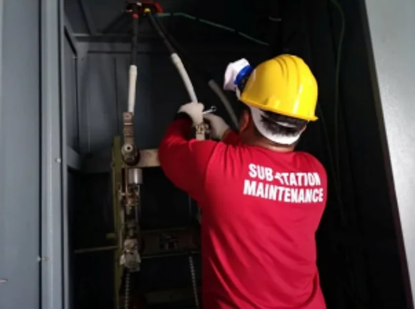 Technician in a hard hat operating equipment inside a switchgear cabinet